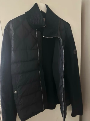 Moncler Cardigan  - Snygg svart/mörkblå cardiganjacka från Moncler med quiltad front och stickade ärmar. Jackan har hög krage, dragkedja framtill och två fickor med knapp. Moncler-logga på ärmen. Perfekt för lager-på-lager och streetstyle. I perfekt skick! ✨