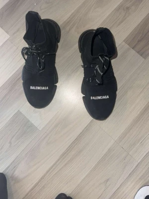 Svarta Balenciaga Speed Trainer sneakers - Svarta Balenciaga Speed Trainer sneakers med stickad ovandel och vita logotexter på tårna. Skorna har svarta och vita snören samt chunky sula i svart. Riktigt clean och modern siluett som sticker ut. Vid en snabb äffar kan gå ner i pris