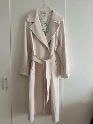 H&M kappa ny med prislapp - Sjukt snygg kappa ifrån H&M i färgen beige, nypris 800kr och prislappen finns kvar. Säljer för 400😍storlek XS men passar S också