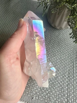 Angel Aura spets - Angel aura spets, 14 cm lång och 240 gram.  Det är bergkristall från Brasilien som utsatts för ett högt tryck i en vakuumkammare som bidrar till den hör underbara och permanenta ytan.   Angel aura kvarts kallas ofta för ” the mood booster”.  Används också för att:  🤍 Höja vibrationerna 🤍 Stärka kontakten med guider & högre medvetande 🤍 Skapa lugn, klarhet och ett skyddande energifält 🤍 Förstärka intentioner och manifestation  Alla kristaller och ädelstenar jag lägger upp här är egenimporterade 