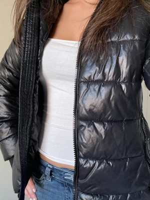 Svart pufferjacka med glansig finish - Fin vinter jacka med glans. 