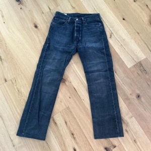 Levi's 501 svart/grå jeans - Klassiska Levi's 501 jeans i mörkblå tvätt med raka ben. Jeansen har knappgylf och är tillverkade i slitstark denim. Perfekta för en avslappnad och tidlös stil.
