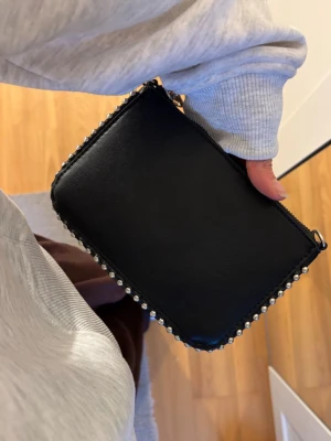 Svart axelväska med silverkedja - Svart simpel enkel handväska med silverdetaljer!! Stilren och snygg - mycketbra skick.