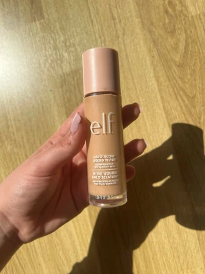 e.l.f. Halo Glow Liquid Filter foundation - e.l.f. Halo Glow Liquid Filter foundation i en snygg glasflaska med beige lock. Flytande formula som ger glow och jämnar ut hudtonen. Färgen är medium beige och flaskan har en stilren design med tydlig logga framtill.
