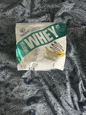 Whey protein Banana Split  - Whey proteinpulver från Swedish Supplements med smaken Banana Split. Förpackningen är vit och grön med bild på banan och choklad. Innehåller 1 kg pulver och medföljer skopa. Perfekt för dig som tränar och vill boosta ditt proteinintag.