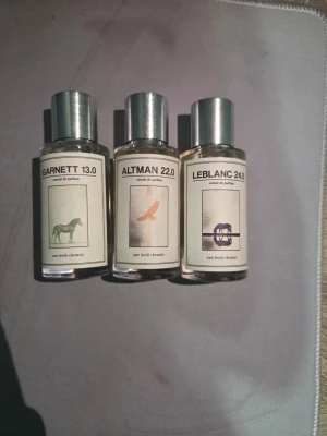 LEBLANC 24.0 ALTMAN 22.0 GARNETT 13.0 - LEBLANC 24.0, ALTMAN 22.0 OCH GARNETT 13.0 är exklusiva parfymer från One Bold Chemist. Flaskorna är genomskinliga med en stilren etikett och har ett silverfärgat lock. Designen är minimalistisk med en grafisk illustration på etiketten. Perfekt för dig som gillar unika dofter och snygg design.