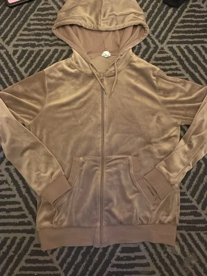 Beige velour hoodie med dragkedja - Mjuk och skön beige hoodie i velourmaterial med dragkedja framtill. Tröjan har huva och ribbade muddar vid ärmslut och nederkant. Tröjan är i jätte bra skick och jag säljer då den blivit för liten och inte kommer till användning. Tveka inte på att höra av dig för fler frågor eller bilder🤗