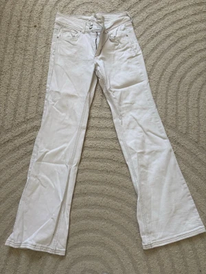 Vita bootcut jeans med låg midja - Snygga vita jeans med bootcut passform och låg midja. Klassisk femficksmodell med dragkedja och knapp framtill. Perfekta för dig som gillar en retrostil och vill sticka ut med ljusa jeans. Materialet är bomull med lite stretch för extra komfort.