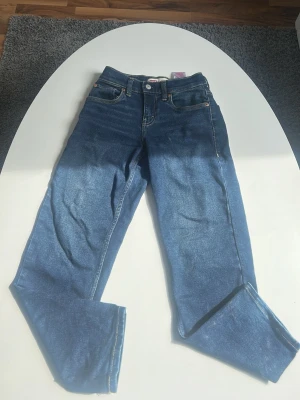 Levi's blå raka jeans - Säljer ett par klassiska blå jeans från Levi's med rak passform och fem fickor. Jeansen har synliga kontrastsömmar och kopparfärgade nitar. Modellen är Loose Taper och materialet är denim i bomull.