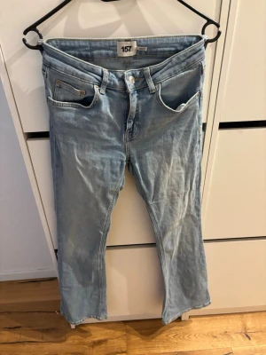 Ljusblå bootcut jeans från 157 - Säljer ett par ljusblå jeans från 157 med bootcut-modell och låg midja. Klassisk femficksdesign och snygga detaljer i silverfärgad metall. Perfekta för dig som gillar en avslappnad och trendig look.