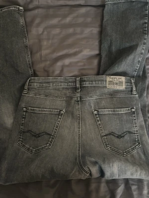 Replay svarta tvättade jeans - Säljer ett par svarta tvättade jeans från Replay med raka ben och klassiska bakfickor med dekorativa sömmar. Jeansen har normal midja, bälteshällor och knappgylf. Materialet är mjukt denim som ger en avslappnad look.
