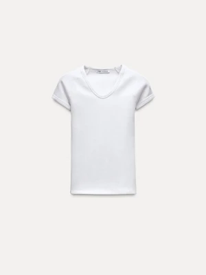 Vit ribbad t-shirt från Zara - Vit ribbad t-shirt från Zara med v-ringning och korta ärmar. T-shirten har en slim passform, liten i storlek. Skulle säga den är en XXS, inte en S. Den är lite skrynklig då en har bara legat i en gadebroben, den aldrig använd. 