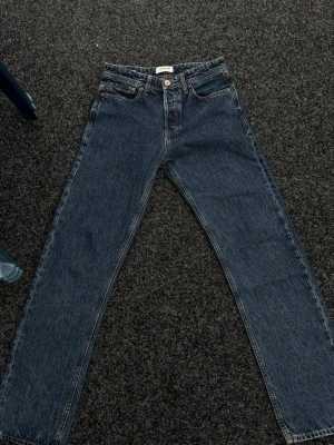 Blå raka jeans från Jack & Jones - Klassiska blå jeans från Jack & Jones med rak passform och fem fickor. Jeansen har en mörk tvätt, kontrastsömmar och läderpatch bak i midjan. Perfekta till en avslappnad stil och tillverkade i bomull.