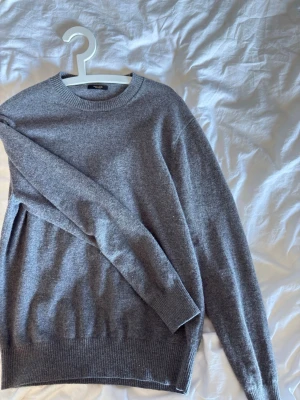 Grå basic stickad tröja Massimo Dutti - En enkel och stilren grå stickad tröja från Massimo Dutti Tröjan har rund halsringning, långa ärmar och ribbade muddar vid ärmslut och nederkant. Perfekt för lager-på-lager och passar till det mesta. Nypris:900 kr