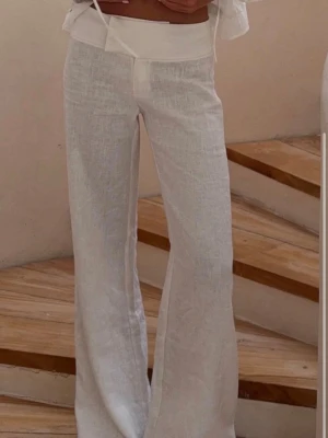 Säljer oanvända Alobha linnebyxor strl XS - Snygga vita linnebyxor med rak och lite vidare passform. Byxorna har hög midja och är tillverkade i ett luftigt linnematerial som ger en avslappnad och trendig look. Perfekta för en stilren och fräsch outfit.