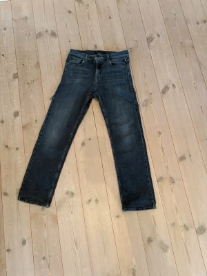 Svarta replay jeans raka - Snygga svarta jeans med rak passform och klassisk femficksdesign. Jeansen har en lätt tvättad look med subtila slitningar på framsidan. Perfekta för en avslappnad och trendig stil. Materialet är bomull. Snabb affär= billigare