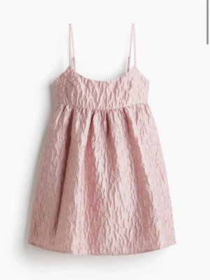 Ljusrosa kort klänning med smala band - Helt ny med lappen på, slutsåld! Köpt för 500kr. Supersöt ljusrosa kort klänning med tunna axelband och strukturerat tyg. Klänningen har en lätt utställd passform och är perfekt för varma dagar. Materialet känns luftigt och ger en unik look.