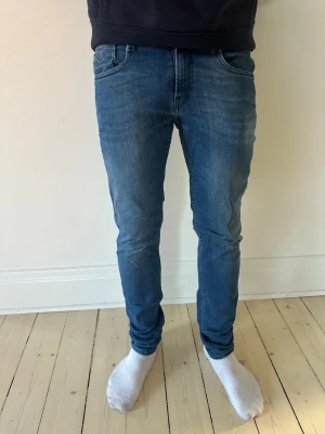 Replay jeans - Säljer ett par blå slim fit jeans från replay med klassisk femficksmodell och snygga slitningar. Jeansen har normal midja, smal passform och är tillverkade i mjuk denim med stretch för extra komfort. Perfekta för en avslappnad och trendig look. Storlek 29