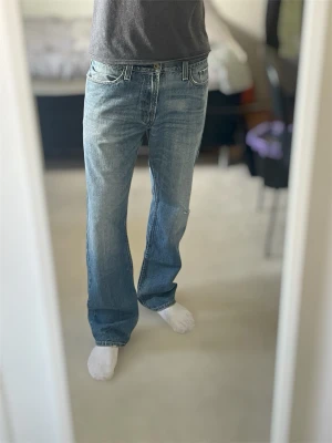 Levi's ljusblå bootcut jeans | 514 Modell | W33 L32 - Säljer ett par ljusblå bootcut jeans från Levi's med klassisk femficksdesign och snygga slitningar. Jeansen har en avslappnad passform och är tillverkade i bomullsdenim. Perfekta för dig som gillar en tidlös och cool look.