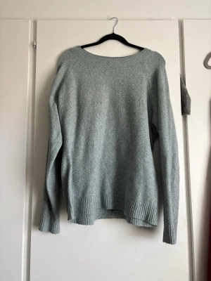 Ljusgrå stickad tröja - En enkel och stilren ljusgrå stickad tröja med rund halsringning och långa ärmar. Tröjan har ribbstickade muddar vid ärmslut och nederkant. Perfekt för lager på lager och passar till det mesta i garderoben.