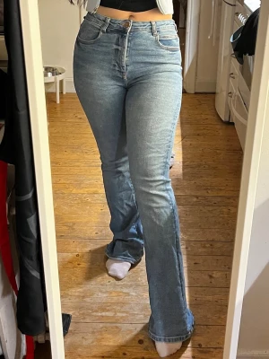 Blå bootcut jeans med hög midja - Det är två olika jeans exakt samma på allt bara olika färger,  säljs separat. Säljer två par snygga blå bootcut jeans med hög midja och klassisk femficksdesign. Jeansen har en lätt tvättad look och är tillverkade i ett stretchigt denimtyg som sitter bekvämt. Perfekta för dig som gillar en retroinspirerad stil.