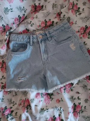 Ljusblå denimshorts från MNG - Säljer ett par ljusblå denimshorts från MNG med råa kanter och slitna detaljer.🥰 Super snygga och rätt så nya. 💫🩵 70 kr + frakt