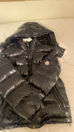 Moncler jacka - Säljer min Moncler Maya då den inte längre kommer till andvändning och bara samlar dam. Allt är som de ska nfc taggen funkar och alla taggar finns, dock är de en knapp som saknas till luvan som ni ser på sista bilden därav de billiga priset. Det går dock enkelt att sätta dit en ny!! Storlek 2 som är monclers M