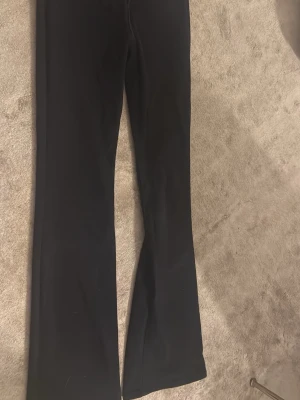 Svarta bootcut jeans Levi's 725 - Säljer ett par svarta Levi's 725 High Rise Bootcut jeans. De har hög midja och utsvängda ben, vilket ger en snygg siluett. Klassisk femficksmodell och tillverkade i stretchigt denimtyg för extra komfort. Perfekta för dig som gillar trendiga och tidlösa jeans.
