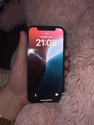 Blå iPhone 12 med slimmad design - Säljer en svart iPhone 12 med modern, slimmad design och platt skärm. Telefonen har en stor, kant-till-kant OLED-skärm och rundade hörn. Tillverkad i glas och aluminium, klassisk Apple-look och passar perfekt i handen.