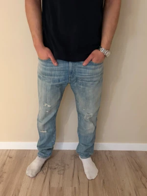 Ljusblå vintage Ralph lauren jeans - Säljer ett par ljusblå jeans  från Ralph lauren med avslappnad passform och slitna detaljer på benen. Jeansen har klassisk femficksdesign och raka ben. Perfekta för en casual och trendig look.