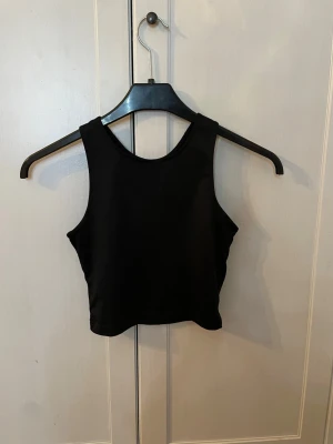 Svart croppad träningstopp - Snygg svart croppad träningstopp från soc. Bra skick men välanvänd vilket ändats syns på loggan i bak. Säljer därför varan för 40kr. OBS! Köparen står för frakt. Pris kan diskuteras. Tror storleken är 146-152 men inte säker, kollar storlek vid intresse. 