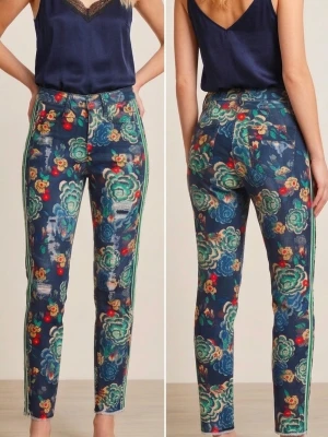 Hög kvalitets jeans med unika mönster - Säljer ett par jeans med färgstarkt blommönster i grönt, blått, rött och gult på mörk botten från Marc Aurel. Modellen har raka ben och sportiga gröna och vita sidoremsor längs båda benen. Materialet är stretchigt och mjukt för extra komfort.