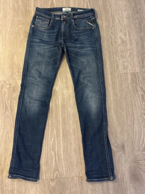 Replay anbass - Snygga blå jeans från Replay med smal passform och klassisk femficksdesign. Jeansen har slitningar och ljusare partier på låren för en cool, använd look. Materialet är denim med kontrastsömmar och detaljerade bakfickor. Köpte i somras för 1799, kom med frågor och prisförslag 