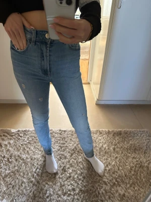 Ljusblå skinny jeans med slitningar - Säljer ett par ljusblå skinny jeans med hög midja och små slitningar på benen. Storlek 36