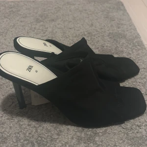Svarta pumps med öppen tå från Zara - Säljer ett par svarta pumps från Zara med öppen tå och fyrkantig framdel. Tillverkade i textilmaterial som känns mjukt och bekvämt på foten. Stories 40 men sitter mer som 30