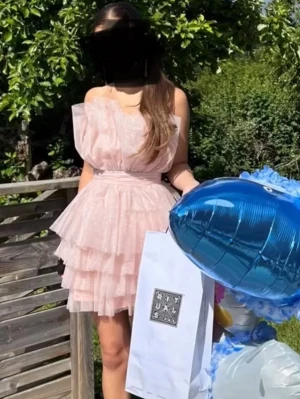 Ljusrosa volangklänning med glitter - Supersöt ljusrosa kortklänning med flera lager volanger och glittrigt tyg. Klänningen är axelbandslös med en asymmetrisk, fluffig överdel och markerad midja. Perfekt för dig som vill sticka ut med en romantisk look.