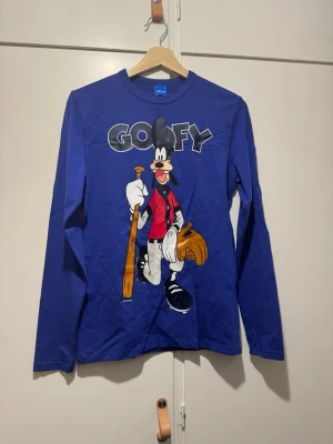 Långärmad tröja - Tröja med roligt tryck i form av Långben/Goofy. Se bilder för enstaka fläckar på tröjans baksida. Vet inte om de går få bort.