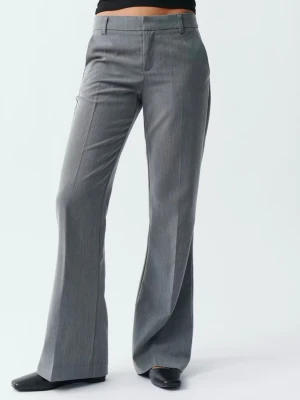 Grå lågmidjande kostymbyxa med utsvängda ben - Snygga grå lågmidjande kostymbyxor med utsvängda ben och pressveck. Byxorna har hällor för skärp, diskreta fickor bak och stängs med dragkedja och hake fram. (Dom är för små för mig så därför tog jag bilder online)