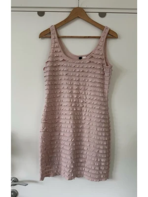 Ljusrosa volangklänning från H&M i storlek 42 - Supersöt rosa / puderrosa klänning med volanger över hela plagget från H&M i storlek 42. Klassisk ärmlös modell med rundad halsringning. Lätt elastisk med tunt foder för bästa passform. Fint skick!