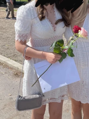 Perfekta studentklänning❤️ - Kort vit klänning i spets med v-ringad hals och markerad midja. Klänningen har korta ärmar med spetsdetaljer och omlottkänsla framtill. Perfekt för sommarens alla tillfällen och studentfirande. Slusåld💕