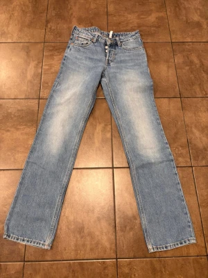 Ljusa weekdayjeans i straight modell - Säljer ett par klassiska ljusblå jeans från weekday. Modellen heter Pin och är raka i modellen och mid waist. Storleken är 26/32. Midjemått tvärs över 35 cm och innerbenslängd 79 cm. Små slitningar längst ner på båda byxben som man ser på sista bilden, annars i bra skick. Nypris var 500 har jag för mig. Skicka ett meddelande om du har frågor. Kan tyvärr inte visa hur dem ser ut på då de ej passar. 🤗
