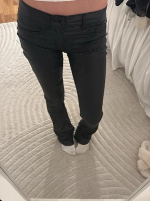 Svarta coated jeans bootcut - skin byxor från only i storlek xs/32 dom är omsydda till lågmidjade och har lite slitningar nere vid fötterna 