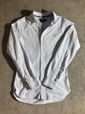 Ljusblå skjorta från Polo Ralph Lauren - Klassisk ljusblå skjorta från Polo Ralph Lauren i slim fit-modell. Skjortan är nästan aldrig använd och är i nyskick nypris:1200kr vs mitt pris:449kr🤩 priset är såklart inte hugget i sten🪨och det är bara att höra av dig om du har några funderingar✅