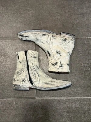 Maison margiela x h&m fw12 re-edition painted boots - Maison Margiela x H&M Painted 2012 re-editon boots  Endast mindre märken från normalt slitage. Jag har lagt till ett skyddande sul-lager så att de är lättare att använda på vintern utan att skada originalsulan. Sulan har också nyligen behandlats (kan skicka en bild som visar hur den ser ut under skyddslagret).  Storlek: 41 Innersula:27 cm