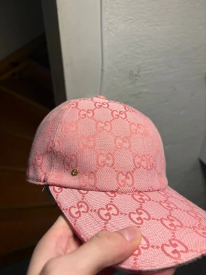 Rosa Gucci keps med GG-mönster - Säljer en snygg rosa keps från Gucci med klassiskt GG-mönster över hela kepsen. Kepsen är äkta aldrig använt!!