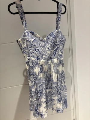 Vit och blå sommarklänning med mönster - Söt kortklänning i vitt med blått mönster. Klänningen har breda axelband. Perfekt för varma dagar eftersom klänningen har en luftig känsla. Såå fin utomlands!🌊💙