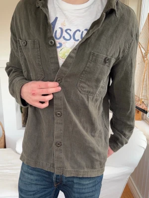 Linne overshirt - Large - Modell: 182cm, 72kg. Sitter lite löst på mig men har en Tisha under. Storlek large, jag brukar oftast ha medium