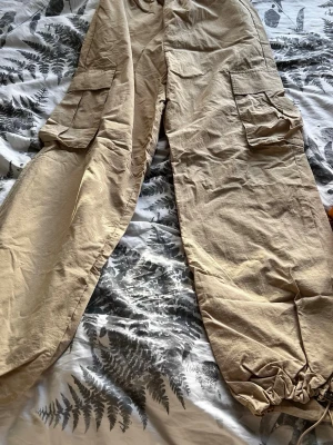 Beige manchester cargobyxor från ONLY - Säljer orphanade beige cargobyxorxer från ONLY med bred resår i midjan, stora fickor på sidorna och dragsko. Sköna sopiga byxor i6 lätt material, perfekta för chill dagar sop streetwear. Passar dig som gillar loose fit och praktiska detaljer.