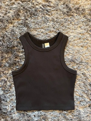 Svart ribbad croppad linnetopp - Säljer en svart croppad linnetopp från H&M Divided. Toppen är ribbad och ärmlös med breda axelband och rund halsringning. Perfekt att matcha med jeans eller kjol för en cool och enkel look. Aldrig använt då den är för liten. Strlk XXS. ALLA PRISER KAN DISKUTERAS🤍