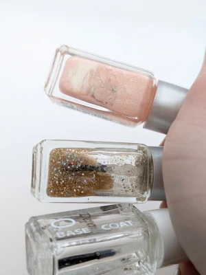 Nagellack set från Depend, 3-pack va hälften kvar. Se bilder - Tre nagellack från Depend: ett persikofärgat med skimmer, ett genomskinligt med guldglitter och färgglada glitterpartiklar samt ett genomskinligt baslack. Små fyrkantiga flaskor med silver- och vitfärgade korkar.